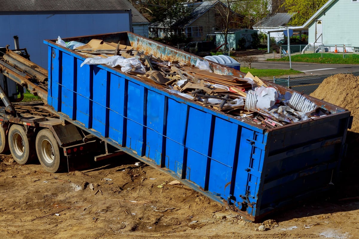 Junk removal truck loading a full waste container